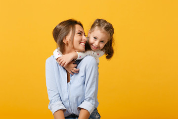 Woman in light clothes have fun with cute child baby girl 4-5 years old. Mommy little kid daughter isolated on yellow background studio portrait. Mother's Day love family parenthood childhood concept.