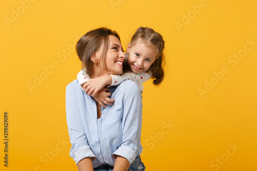 Woman in light clothes have fun with cute child baby girl 4-5 years old. Mommy little kid daughter isolated on yellow background studio portrait. Mother's Day love family parenthood childhood concept. photo