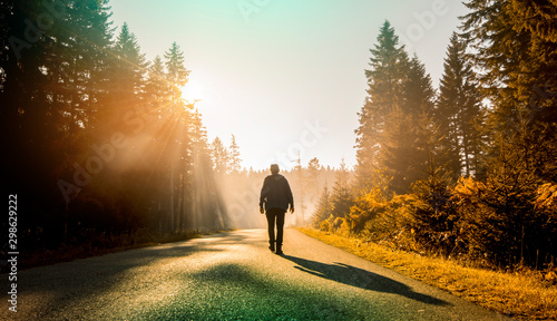 Fototapeta Naklejka Na Ścianę i Meble -  man walking on country road at sunset