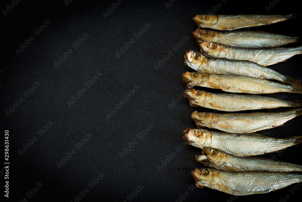 Smoked sprats on a dark background with empty space for your own text Smoked sprats on a dark background with empty space for your own text
