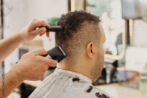 Barber making stylish haircut with professional machine in barber shop. Hair cut for turkish man