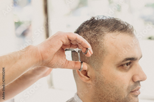 Barber making stylish haircut with professional scissers in barber shop. Hair cut for turkish man