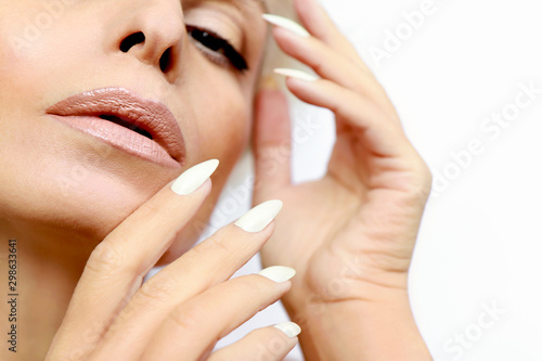 Portrait of a woman with clean healthy skin and a long manicure with milk nail Polish close-up.