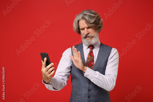 Принти на полотні Displeased elderly gray-haired mustache bearded man in shirt vest colorful tie posing isolated on red background