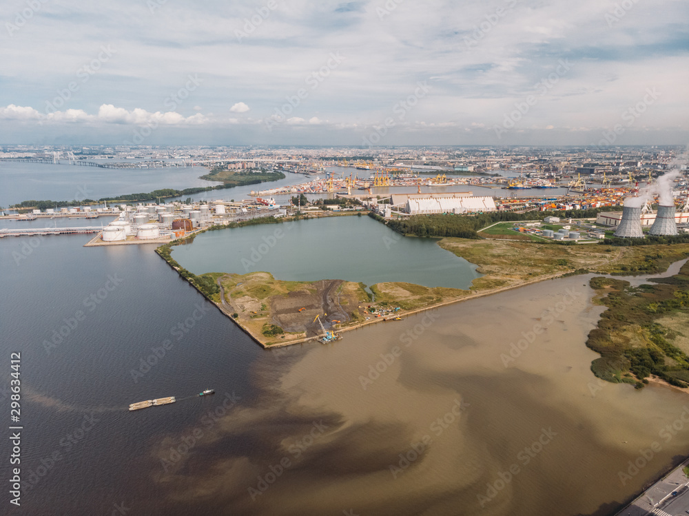 Gulf with dirty water from thermal power plant. Heat generation, environmental pollution. Cargo port in the background. International sea freight. Industrial zone. Save earth concept. Aerial view.