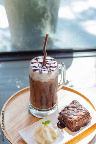 Ice coffee a late art in the glass on the table background, chockolate cake in wooden tray, photo