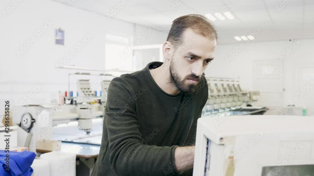 Man working on computer of sewing machine Man working on computer of sewing machine