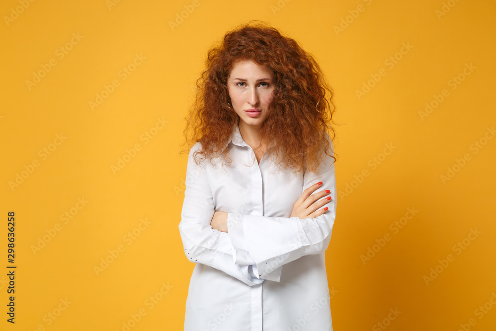 Displeased young redhead woman girl in casual white shirt posing isolated on yellow orange background in studio. People sincere emotions lifestyle concept. Mock up copy space. Holding hands crossed. Displeased young redhead woman girl in casual white shirt posing isolated on yellow orange background in studio. People sincere emotions lifestyle concept. Mock up copy space. Holding hands crossed.