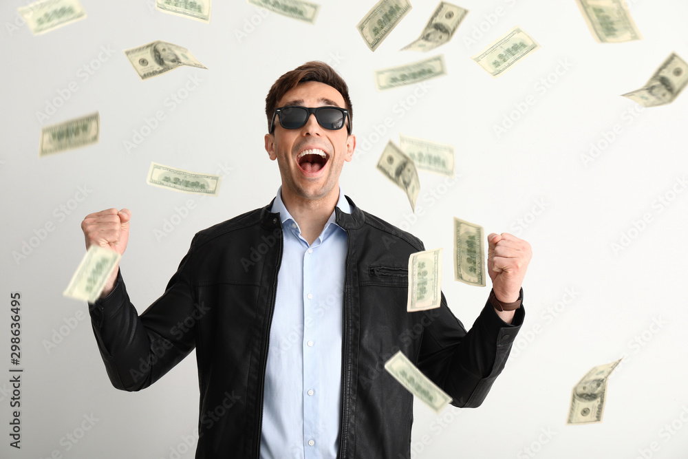 Happy young man and falling dollar banknotes on white background Happy young man and falling dollar banknotes on white background