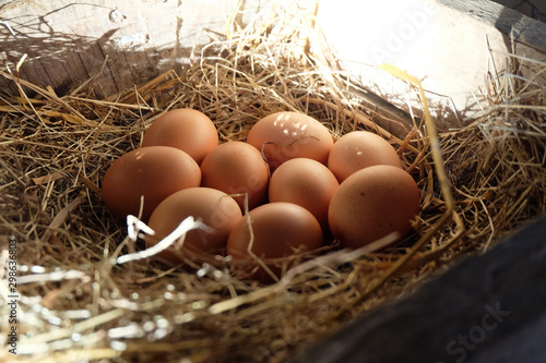 Close-up​ of​ fresh chicken eggs with nest​ in​ the​ wood​en​ box, A pile of brown eggs in a nest.