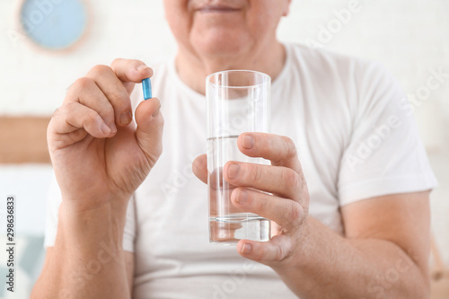 Elderly man taking medicine at home, closeup © Pixel-Shot