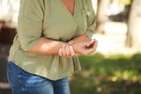 Mature woman suffering from pain in wrist outdoors