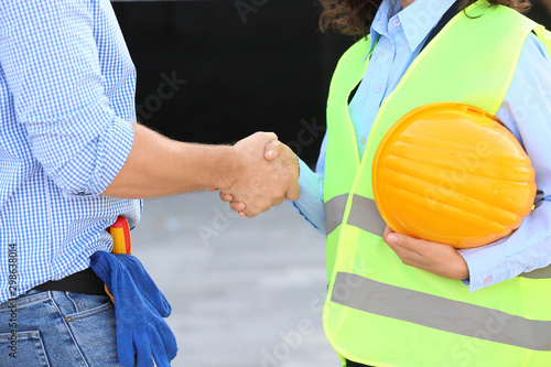 Architect and builder shaking hands in building area