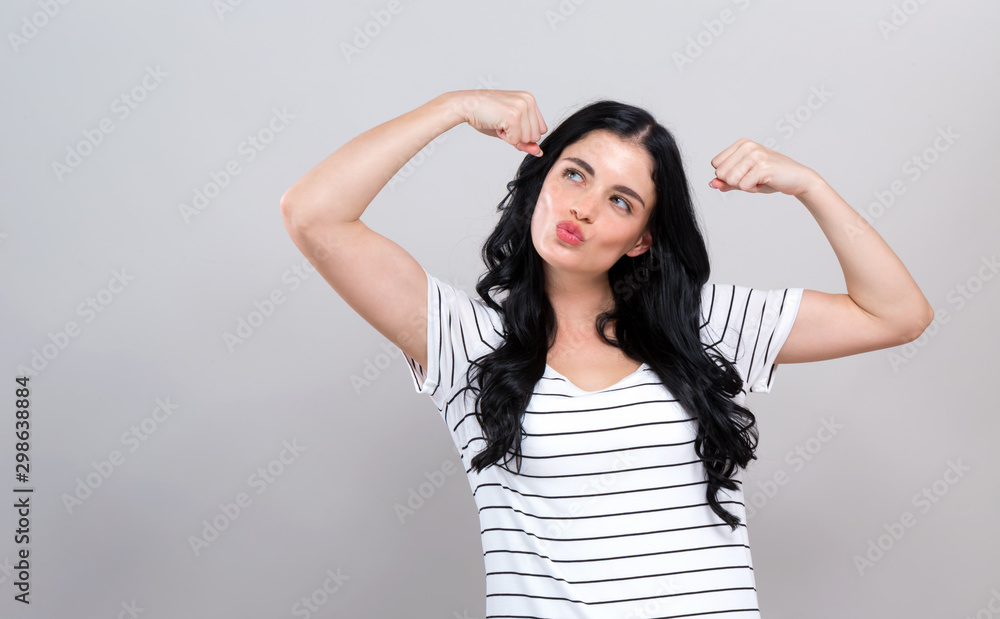 Powerful young woman in a success pose on a gray background