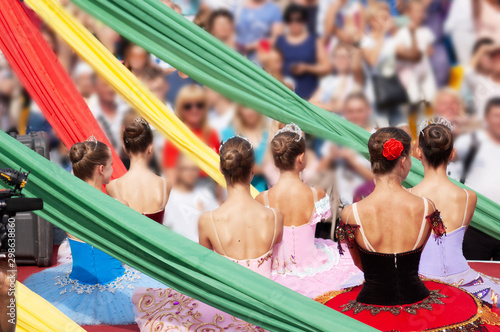 carnival procession of people dressed in costumes through the streets of the city, day of the city, girls in costumes of ballerinas on the platform in front of many people