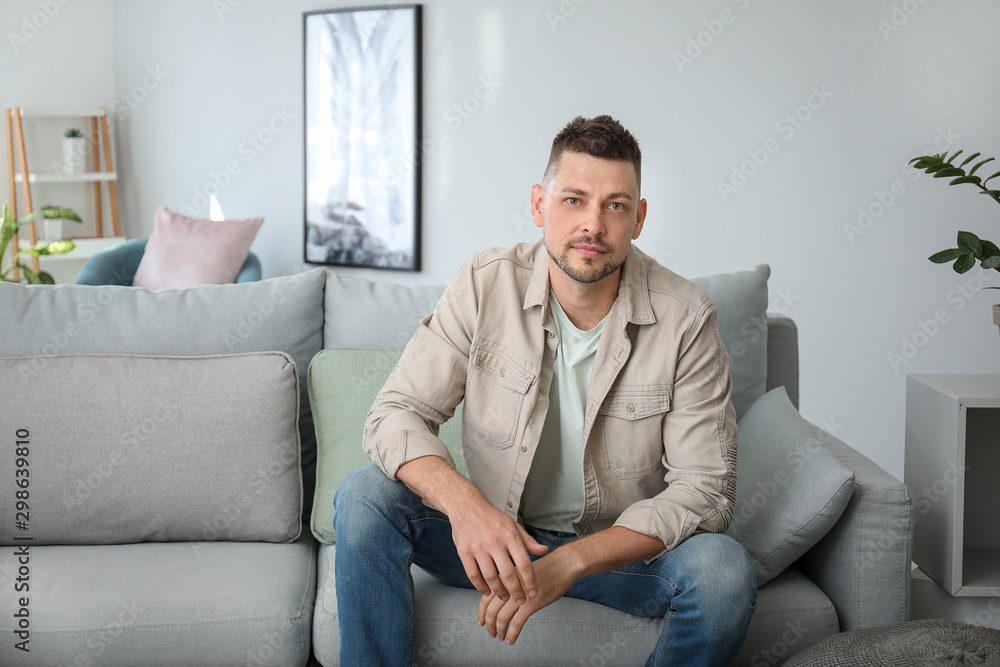 Portrait of handsome man sitting on sofa at home