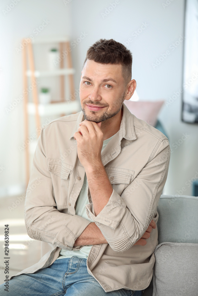 Fototapeta premium Portrait of handsome man sitting on sofa at home