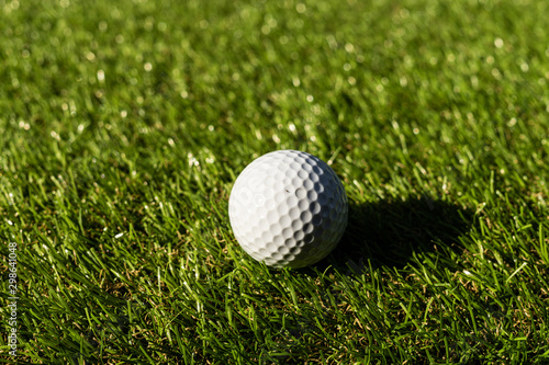 Golf ball on the green,Green grass with golf ball close-up in soft focus at sunlight. Sport playground for golf club concept - wide landscape as background for your lettering about golf playing.
