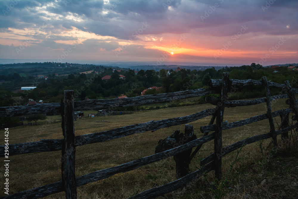 Fototapeta premium Sun is rising behind the clouds above hills of Serbia rural landscape region