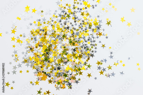 Small golden stars confetti on white background. Top view. Flat lay