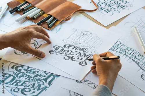 Tablou pe pânză Typography Calligraphy artist designer drawing sketch writes letting spelled pen brush ink paper table artwork