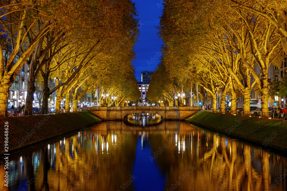 Night view over canal and beautiful waterside area at Königsallee, famous shopping street, and background of Girardet-Brücke in Düsseldorf, Germany.