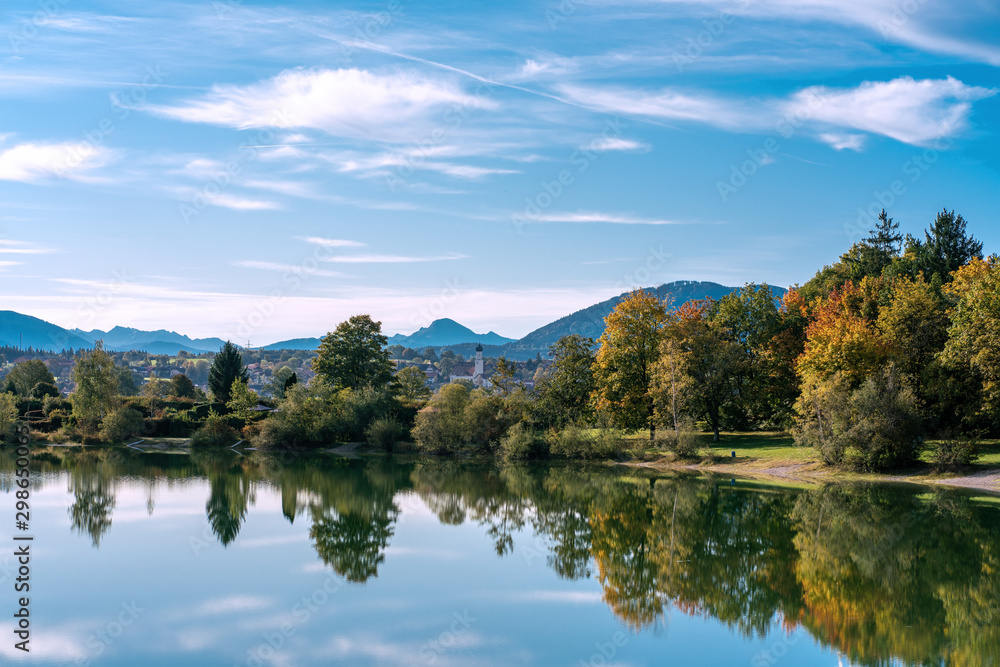 The village and church of Koenigsdorf in Bavaria with the Bibi Lake in the foreground and the mountains in the background The village and church of Koenigsdorf in Bavaria with the Bibi Lake in the foreground and the mountains in the background