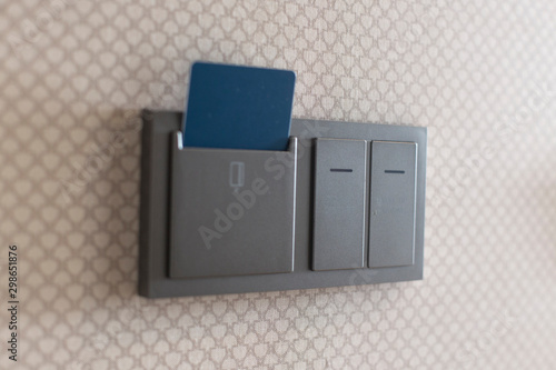 Electronic lock with card inserted and light switches on concrete wall in hotel room
