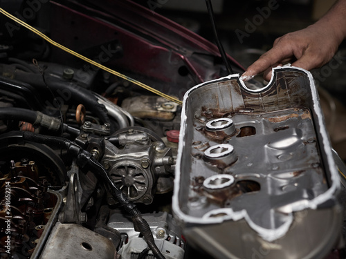 Auto mechanic working in garage. Put the glue on the cover part. Authentic close-up.