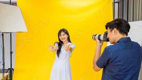 Happy model women show hand sign love Portrait of a photographer and women model,   Behind the shooting production crew team camera and equipment in studio photography concept