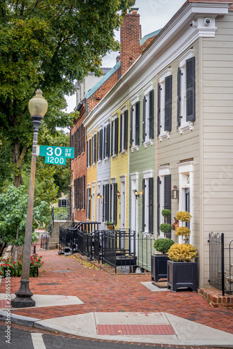 View of colonial row house, townhome, with colorful, yellow, blue, green vinyl siding on a quiet street in Georgetown Washington DC USA photo