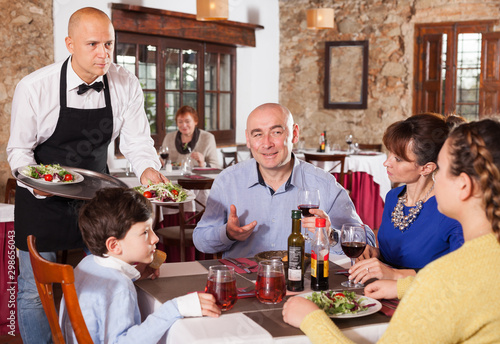 Waiter serving dishes to family
