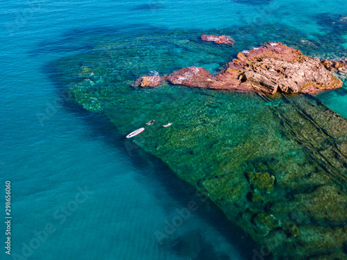 Aerial view of a paddle board in the water floating on a transparent sea, snorkeling. Bathers at sea. Tropea, Calabria, Italy. Diving relaxation and summer vacations. Italian coasts, beaches and rocks