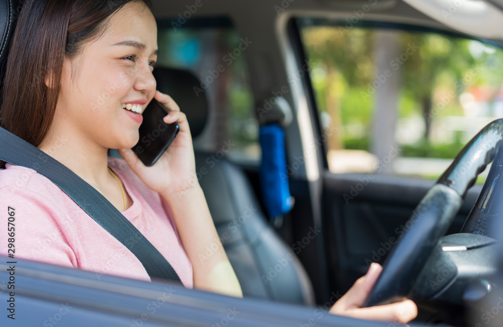 Happy young Asian girls using or talking smart phone while driving the car. Dangerous driver, transportation and vehicle or Road safety concept Happy young Asian girls using or talking smart phone while driving the car. Dangerous driver, transportation and vehicle or Road safety concept