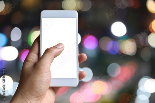 Hand of a man holding smartphone device in the bokeh background.