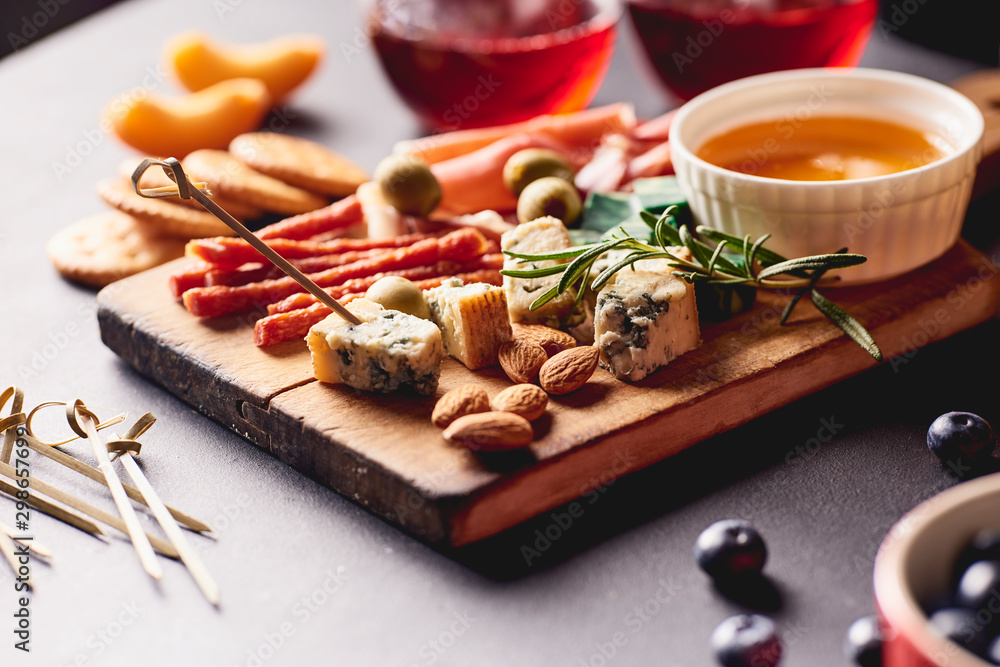 Red wine with different kinds of cheese, charcuterie assortment, crackers, grapes, nuts and berries - obrazy, fototapety, plakaty 
