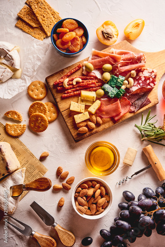 Red wine with different kinds of cheese, charcuterie assortment, crackers, grapes, nuts