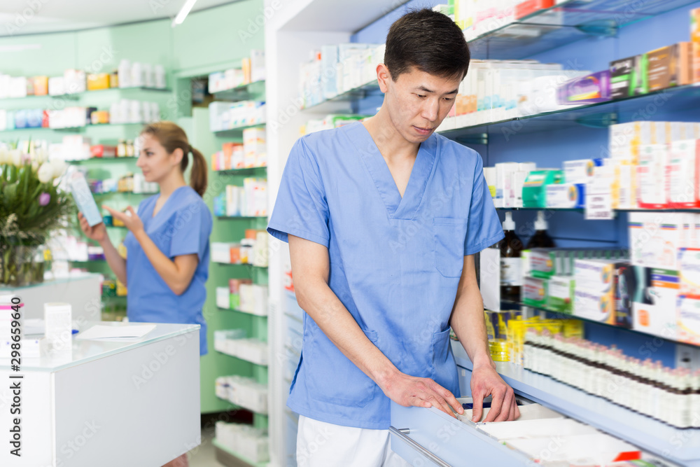 Man pharmacist is searching medicines on shelves