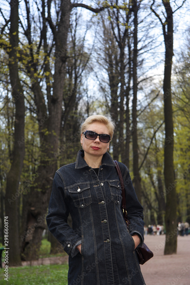 A beautiful woman in dark glasses , against the background of trees, looks at the camera, A beautiful woman in dark glasses , against the background of trees, looks at the camera,
