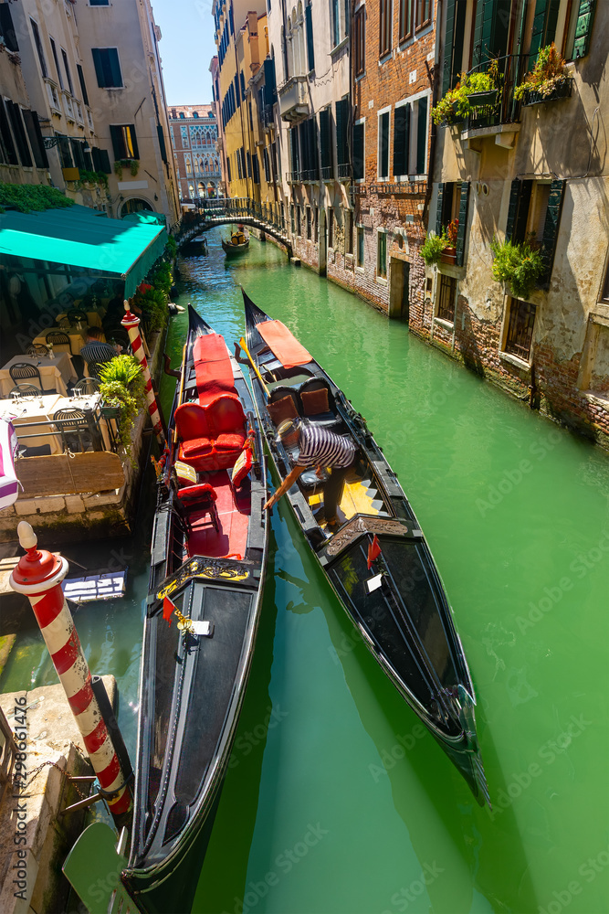 Gondolier mooring gondola in Venetian canal