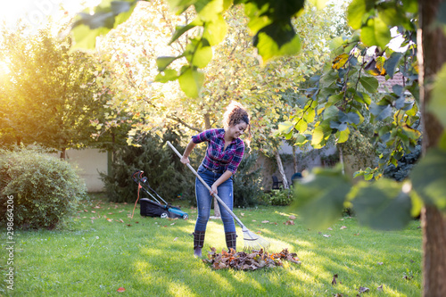 Obraz na płótnie Woman raking leaves on lawn