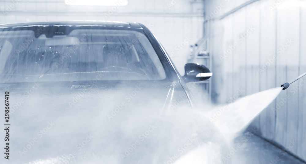 Obraz premium Car washing service. Worker cleaning auto using high pressure water