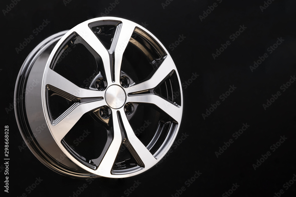 Obraz premium new cast aluminum wheel disc close up on black background. forked spokes, black and polished surface, copyspace,