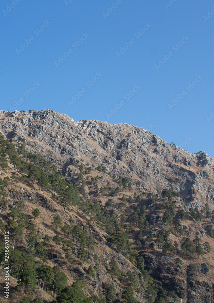 Portrait view of a mountain top shot from a low angle with vast blue sky in the background. Nature concept