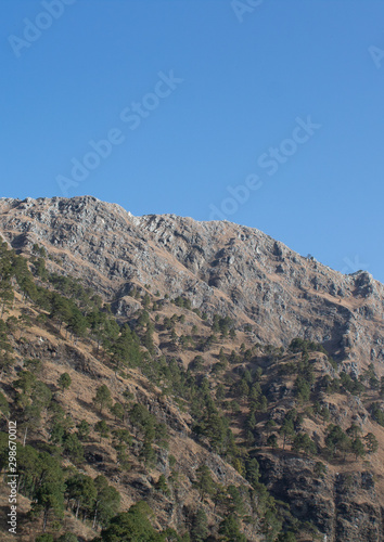 Portrait view of a mountain top shot from a low angle with vast blue sky in the background. Nature concept © PhotoPooja