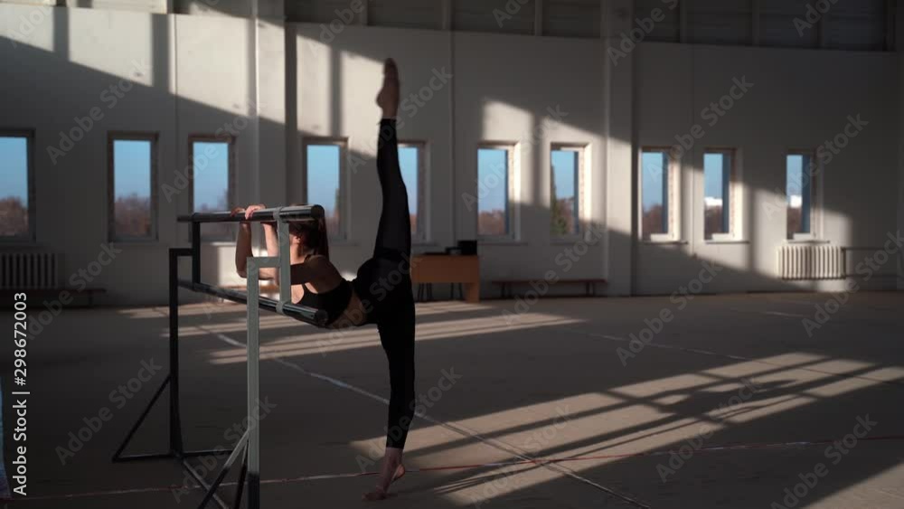Flexible little girl gymnast doing acrobatic exercise in bright gym. Sport, training, fitness, yoga, active lifestyle concept Flexible little girl gymnast doing acrobatic exercise in bright gym. Sport, training, fitness, yoga, active lifestyle concept