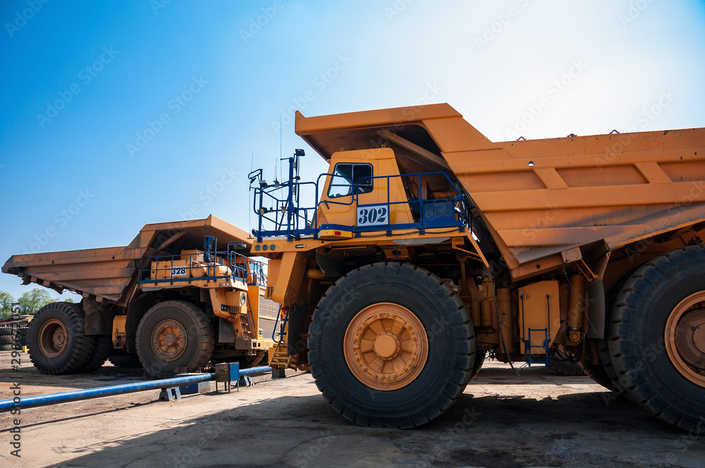 heavy yellow quarry dump truck at repair station at sunny cloudless day heavy yellow quarry dump truck at repair station at sunny cloudless day