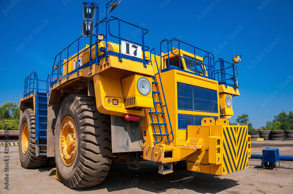 Heavy yellow quarry tractor at repair station at sunny cloudless day