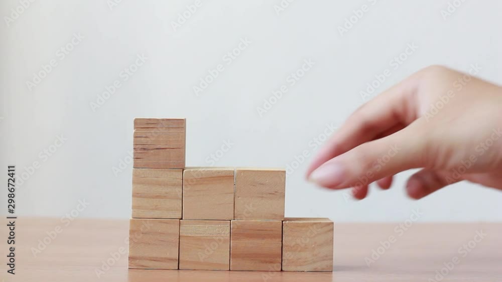 Hand putting wood cube on top of wood block stacking as step stair.business growth to success.