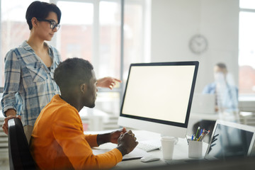 Side view portrait of two modern young people looking at blank white computer screen while working on startup project in office, copy space